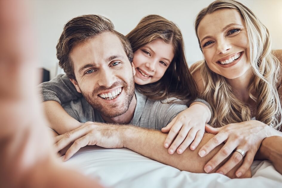 Familia feliz compartiendo un momento de alegría, con sonrisas brillantes gracias al cuidado dental integral.